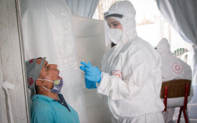 Les personnels médicaux du Magen David Adom réaliser des prélèvements pour dépister le nouveau coronavirus, dans le sud de Tel Aviv, le 2 juin 2020 (Crédit : Miriam Alster/Flash90) Les personnels médicaux du Magen David Adom réaliser des prélèvements pour dépister le nouveau coronavirus, dans le sud de Tel Aviv, le 2 juin 2020 (Crédit : Miriam Alster/Flash90)