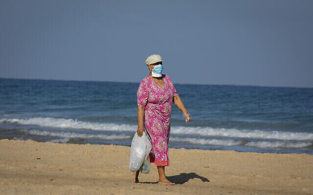Une femme israélienne portant un masque marche sur la plage de la ville côtière d'Ashdod, dans le sud du pays, le 12 juin 2020 (Crédit : Olivier Fitoussi/Flash90) Une femme israélienne portant un masque marche sur la plage de la ville côtière d'Ashdod, dans le sud du pays, le 12 juin 2020 (Crédit : Olivier Fitoussi/Flash90)