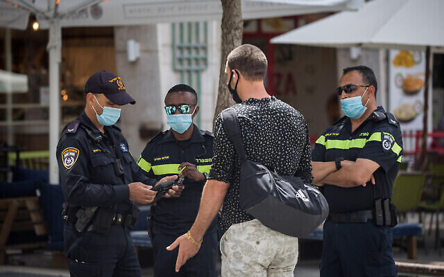 Un homme reçoit un avertissement d'un officier de police pour absence de port d'un masque dans la rue Jaffa, dans le centre de Jérusalem, le 21 juin 2020. (Yonatan Sindel/Flash90)