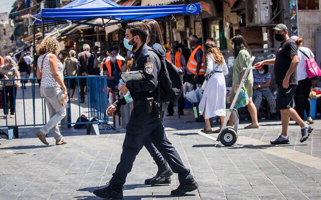 Des agents de police font appliquer les directives de distanciation physique au marché Mahane Yehuda, à Jérusalem, le 25 juin 2020 (Crédit : Yonatan Sindel/Flash90) Des agents de police font appliquer les directives de distanciation physique au marché Mahane Yehuda, à Jérusalem, le 25 juin 2020 (Crédit : Yonatan Sindel/Flash90)