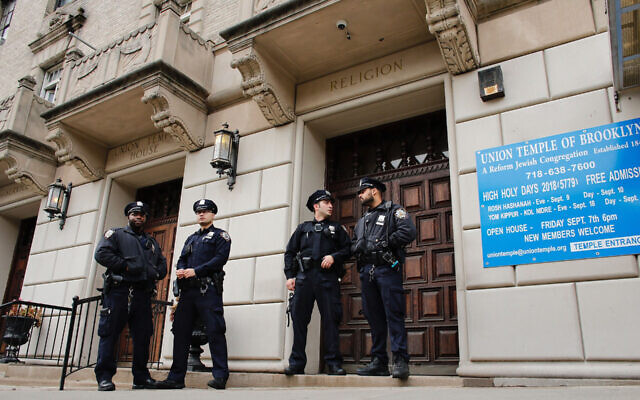 Des agents de la police de New York montent la garde à l'entrée de l'Union Temple de Brooklyn après sa profanation par des graffitis, le 2 novembre 2018 (Crédit :  Kena Betancur/AFP via Getty Images)