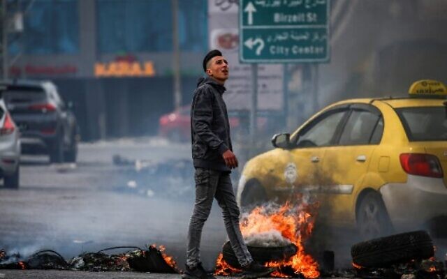 Un Palestinien marche à côté de pneus en feu au cours d'affrontements avec les forces israéliennes à l'entrée nord de la ville cisjordanienne de Ramallah, le 14 février 2020. (ABBAS MOMANI/AFP) Un Palestinien marche à côté de pneus en feu au cours d'affrontements avec les forces israéliennes à l'entrée nord de la ville cisjordanienne de Ramallah, le 14 février 2020. (ABBAS MOMANI/AFP)