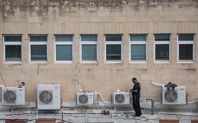Un ouvrier installant des climatiseurs sur le toit d'un immeuble de bureaux dans le centre de Jérusalem, le 8 février 2018. (Crédit : Nati Shohat/Flash90) Un ouvrier installant des climatiseurs sur le toit d'un immeuble de bureaux dans le centre de Jérusalem, le 8 février 2018. (Crédit : Nati Shohat/Flash90)