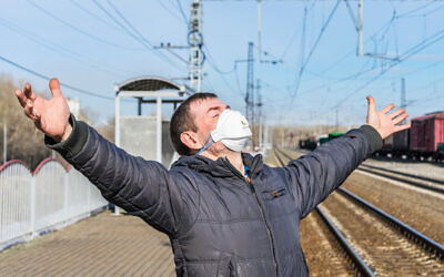 Image d’illustration : un homme heureux, guéri de la maladie, debout dans une gare portant un masque. (Crédit : iStock / Nikolay Chekalin)