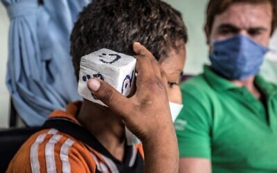 Un travailleur social joue à un jeu avec un enfant des rues dans l'une des unités mobiles gérées par les autorités égyptiennes et utilisé dans le cadre du programme social "Atfal bala ma'wa" (Enfants sans foyer), dans le quartier de l'Abbasia, dans la capitale du Caire, le 22 juin 2020. (Khaled DESOUKI / AFP)