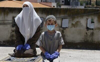 Les membres de la famille d'un imam local font leur prière du vendredi sur le toit de leur maison après la fermeture des mosquées par l'Autorité palestinienne pour cause de coronavirus à Hébron, en Cisjordanie, le 3 juillet 2020. (Crédit : Hazem Bader/AFP)