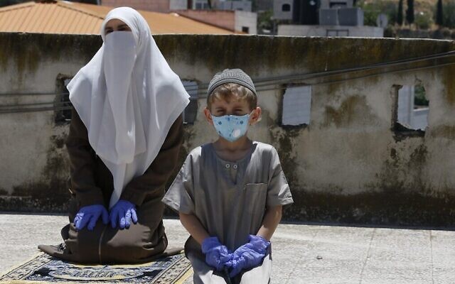 Les membres de la famille d'un imam local font leur prière du vendredi sur le toit de leur maison après la fermeture des mosquées par l'Autorité palestinienne pour cause de coronavirus à Hébron, en Cisjordanie, le 3 juillet 2020. (Crédit : Hazem Bader/AFP)