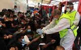 Un agent de santé italien donne des bracelets numérotés aux migrants secourus en mer sur le navire de sauvetage « Ocean Viking », exploité par l'ONG française SOS Méditerranée en mer Méditerranée, le 5 juillet 2020. (Crédit : Shahzad ABDUL / AFP)