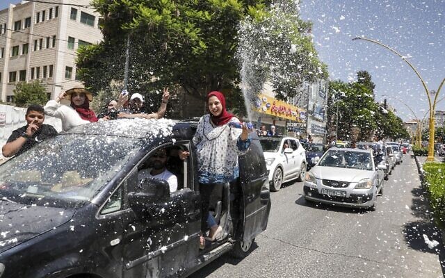 Des lycéens palestiniens lancent de la neige artificielle depuis une voiture alors qu'ils fêtent l'annonce des résultats des examens finaux du lycée à Hébron, en Cisjordanie, le 11 juillet 2020 (Crédit : HAZEM BADER / AFP) Des lycéens palestiniens lancent de la neige artificielle depuis une voiture alors qu'ils fêtent l'annonce des résultats des examens finaux du lycée à Hébron, en Cisjordanie, le 11 juillet 2020 (Crédit : HAZEM BADER / AFP)