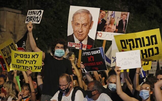 Des manifestants israéliens brandissent des panneaux contre le Premier ministre Benjamin Netanyahu à Jérusalem, le 23 juillet 2020 (Crédit : Ahmad GHARABLI / AFP)