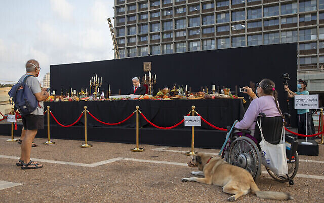 Des passants prennent en photo l'installation de l'artiste israélien Itay Zalait se moquant du Premier ministre Benjamin Netanyahu en reprenant "La Cène", sur la place Rabin à Tel Aviv, le 29 juillet 2020. (Crédit : Oded Balilty/AP) Des passants prennent en photo l'installation de l'artiste israélien Itay Zalait se moquant du Premier ministre Benjamin Netanyahu en reprenant "La Cène", sur la place Rabin à Tel Aviv, le 29 juillet 2020. (Crédit : Oded Balilty/AP)