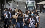 Une femme utilise son téléphone portable alors que des personnes portent des masques de protection par peur du coronavirus dans le centre-ville de Jérusalem, le 8 juin 2020. (Olivier Fitoussi/Flash90)