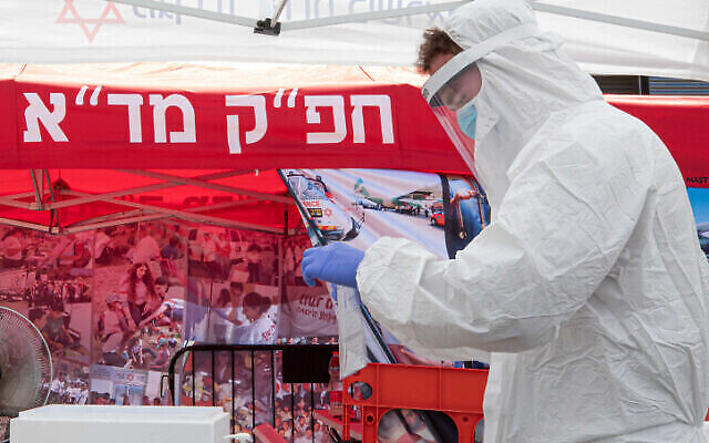 Un médecin du Magen David Adom teste des Israéliens sur un site de drive-in pour prélever des échantillons en vue d'un dépistage de coronavirus, le 10 juillet 2020. (Chen Leopold/Flash90) Un médecin du Magen David Adom teste des Israéliens sur un site de drive-in pour prélever des échantillons en vue d'un dépistage de coronavirus, le 10 juillet 2020. (Chen Leopold/Flash90)