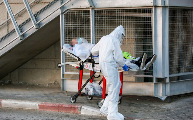 Un salarié du Magen David Adom portant des vêtements de protection évacue un patient atteint du coronavirus à l'extérieur de l'unité coronavirus du centre médical Ziv dans la ville de Tzfat, dans le nord d'Israël, le 19 juillet 2020. (David Cohen / Flash90)