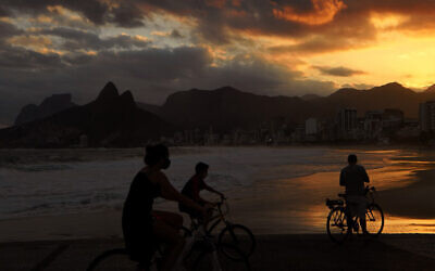 Des cyclistes portent des masques sur la plage d' Ipanema à Rio de Janeiro, au Brésil, le 2 juillet 2020 (Crédit : Carl de Souza/AFP)