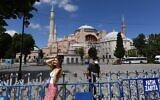 Une femme prend la pose devant la Basilique Sainte-Sophie à Istanbul, le 11 juillet 2020. (Crédit : Ozan Kose/AFP)
