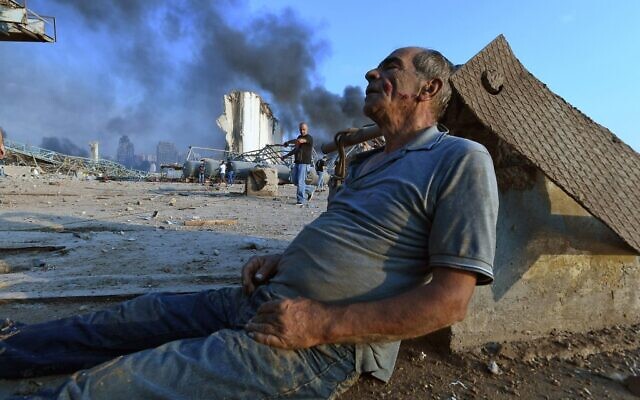Un homme est assis au sol en attendant de l'aide au port de Beyrouth après l'énorme explosion qui a frappé le coeur de la capitale libanaise le 4 août 2020. 
(Photo by - / AFP)