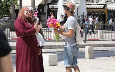 Un activiste du groupe Tag Meir, un groupe israélien financé par le New Israel Fund, donne des fleurs dans la lutte contre le racisme à Jérusalem, le 1er juin 2019 (Crédit : NIF/Yossi Zamir via JTA)