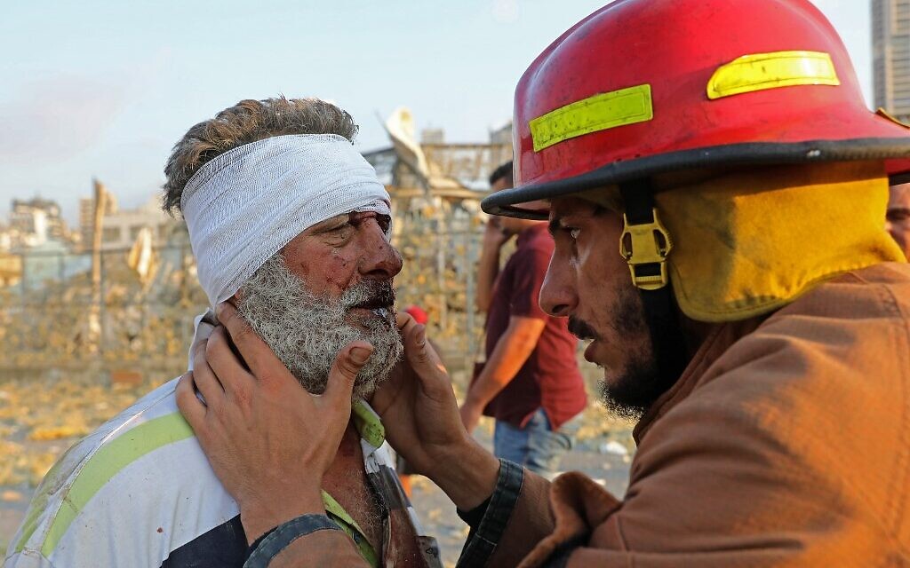 Un blessé est examiné par un pompier aux abords du site d'une explosion à Beyrouth, le 4 août 2020. (Crédit :  Anwar AMRO/AFP)