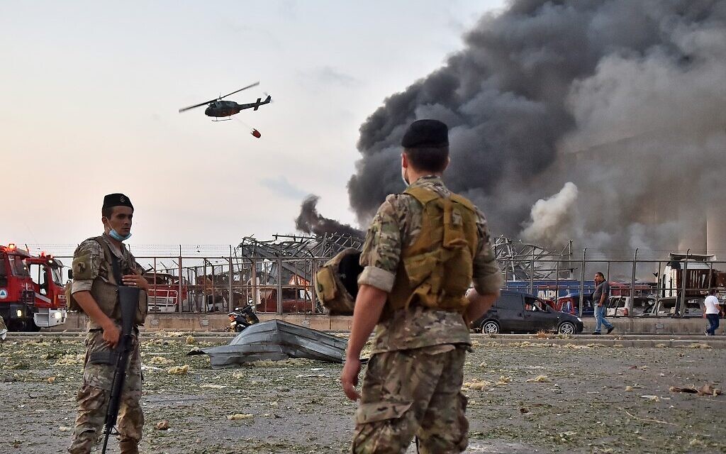 Des soldats libanais regardent un hélicoptère éteindre un incendie sur la scène d'une explosion dans le port de Beyrouth, capitale du Liban, le 4 août 2020. (Crédit : STR / AFP)
