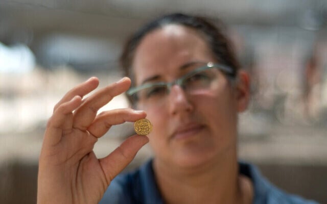 Liat Nadav-Ziv, directrice des fouilles, tient une pièce d'or. (Crédit : Yoli Schwartz, Israel Antiquities Authority)