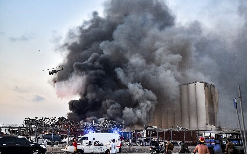 Un hélicoptère éteint un feu sur le site d'une explosion au port de la capitale libanaise Beyrouth, le 4 août 2020. (Crédit : STR / AFP)