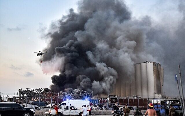 Un hélicoptère éteint un feu sur le site d'une explosion au port de la capitale libanaise Beyrouth, le 4 août 2020. (Crédit : STR / AFP) Un hélicoptère éteint un feu sur le site d'une explosion au port de la capitale libanaise Beyrouth, le 4 août 2020. (Crédit : STR / AFP)