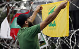 Un partisan du Hezbollah scande des slogans en brandissant le drapeau de l'organisation terroriste durant une manifestation contre l'intervention américaine dans les affaires du Liban, près de l'ambassade des Etats-Unis à Aukar, au nord-est de Beyrouth, le 10 juin 2020. (Crédit : AP Photo / Hussein Malla)