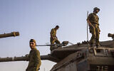 Des soldats israéliens travaillent sur des tanks aux abords de la frontière avec le Liban, le 28 juillet 2020 (Crédit : AP Photo/Ariel Schalit)
