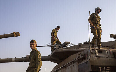 Des soldats israéliens travaillent sur des tanks aux abords de la frontière avec le Liban, le 28 juillet 2020 (Crédit : AP Photo/Ariel Schalit)
