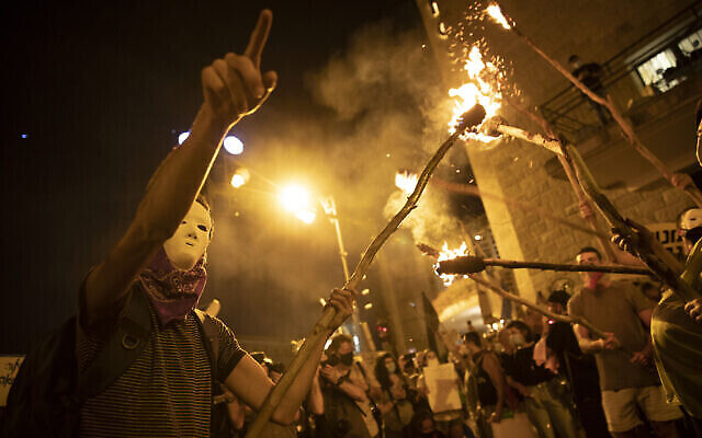 Des manifestants brandissent des torches durant une manifestation contre le Premier ministre Benjamin Netanyahu aux abords de sa résidence officielle de Jérusalem, le 2 août 2020 (Crédit : AP Photo/Oded Balilty)