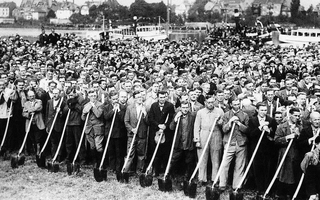 Des ouvriers avec des pelles écoutent Adolf Hitler parler alors que les travaux commencent sur la Reichsautobahn (autoroute) de Francfort-sur-le-Main à Heidelberg, le 23 septembre 1933. (AP Photo)