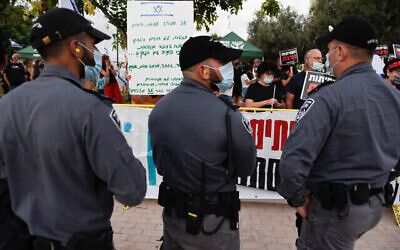 Des agents de police devant des manifestants protestant contre le Premier ministre Benjamin Netanyahu près de sa résidence située dans la ville côtière de Césarée, le 8 août 2020 (Crédit : Meir Vaknin/Flash90)