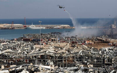 Un hélicoptère de l'armée libanaise larguant de l'eau sur la scène de l'explosion qui a frappé la zone du port de Beyrouth, au Liban, le 5 aout 2020. (Crédit : Hussein Malla/AP)