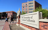 Passants devant le panneau du University Village de l'University of Southern California à Los Angeles, le 12 mars 2019. (Crédit : AP Photo/Reed Saxon, File)