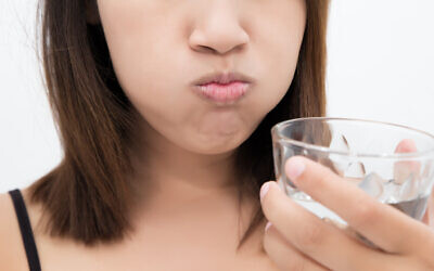 Image d'illustration : Une femme se gargarise en utilisant du bain de bouche dans un verre. (Tharakorn ; iStock by Getty Images)