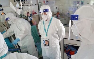 Sur cette photo du Ministère de la Santé, le ministre de la Santé Yuli Edelstein (centre) rend visite à des patients du service Coronavirus du centre médical Yitzhak Shamir à Tzrifin le 23 juillet 2020. (Autorisation : Ministère de la Santé)