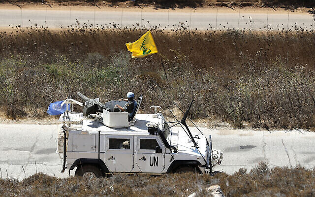Des casques bleus espagnols de l'ONU patrouillant le long de la frontière israélo-libanaise passent devant un drapeau du Hezbollah, dans le village de Kfar Kila, au sud du Liban, le 2 septembre 2019. (Crédit : AP Photo/Hussein Malla)