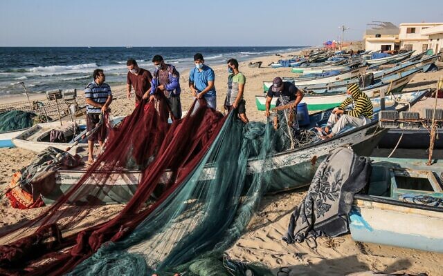 Des pêcheurs palestiniens, masqués en raison de la pandémie de coronavirus COVID-19, préparent leurs filets de pêche sur une plage de la Méditerranée à Rafah, dans le sud de la bande de Gaza, le 2 septembre 2020. (SAID KHATIB / AFP)
