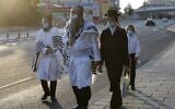 Des Juifs ultra-orthodoxes portant le masque vont à la synagogue en empruntant une rue vide pour les prières de Rosh Hashana à Jérusalem dans le cadre du nouveau confinement national, le 19 septembre 2020 (Crédit : Menahem Kahana/AFP)
