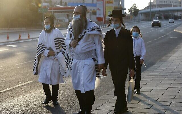 Des Juifs ultra-orthodoxes portant le masque vont à la synagogue en empruntant une rue vide pour les prières de Rosh Hashana à Jérusalem dans le cadre du nouveau confinement national, le 19 septembre 2020 (Crédit : Menahem Kahana/AFP) Des Juifs ultra-orthodoxes portant le masque vont à la synagogue en empruntant une rue vide pour les prières de Rosh Hashana à Jérusalem dans le cadre du nouveau confinement national, le 19 septembre 2020 (Crédit : Menahem Kahana/AFP)