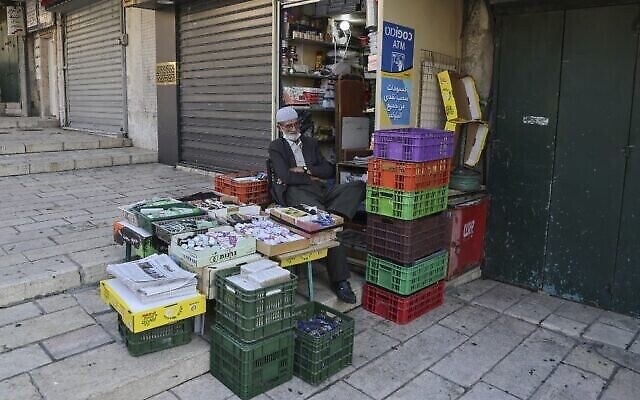 Le propriétaire palestinien d'un magasin assis près de sa marchandise dans une rue vide de la Veille Ville de Jérusalem dans le cadre du nouveau confinement national, le 19 septembre 2020 (Crédit :  Menahem Kahana/AFP)