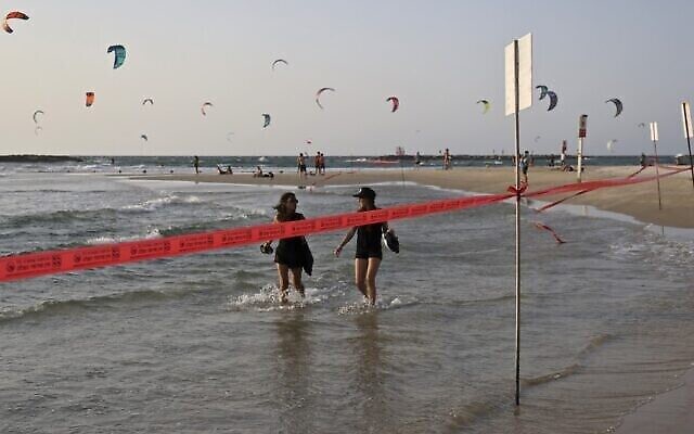 Des kite-surfers et des amateurs de plage sur une plage fermée de Tel Aviv durant le confinement national, le 19 septembre 2020 (Crédit : Menahem Kahana/AFP)