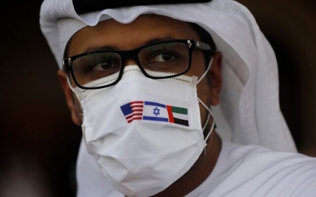 Un homme porte un masque avec les drapeaux américain, israélien et émirati en regardant une cérémonie après l'atterrissage d'un avion El Al à Abu Dhabi, aux EAU, le 31 août 2020 (Crédit : Nir Elias/Pool via AP) Un homme porte un masque avec les drapeaux américain, israélien et émirati en regardant une cérémonie après l'atterrissage d'un avion El Al à Abu Dhabi, aux EAU, le 31 août 2020 (Crédit : Nir Elias/Pool via AP)