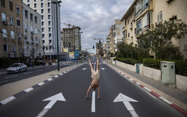 Un Israélien se tient sur les mains sur une route déserte pendant le bouclage qui fait suite aux mesures gouvernementales visant à stopper la propagation du coronavirus, à Tel Aviv, le 8 avril 2020. (AP Photo/Oded Balilty)
