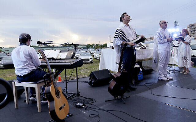 Le rabbin Jonathan Berkun, au centre, dirige un office pour Yom Kippour organisé par le centre juif  Aventura Turnberry, auquel les fidèles assisent depuis leurs voitures en pleine pandémie de coronavirus,  dans un cinéma en plein air de Dezerland Park, à North Miami, en Floride, le 28 septembre 2020 (Crédit : AP Photo/Lynne Sladky)