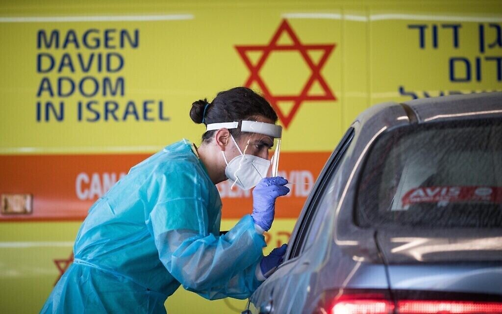 Une employée de Shaare Zedek, vêtue de son habit de protection, prélève un échantillon en vue d'un test de dépistage à la COVID-19 aux abords de l'unité de coronavirus de Shaare Zedek,; à Jérusalem, le 4 septembre 2020)