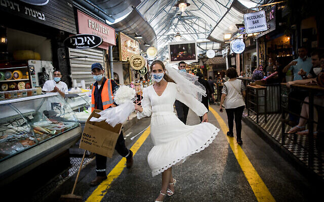Une mariée israélienne avec un masque facial se promène au marché Mahane Yehuda à Jérusalem le 15 septembre 2020. (Yonatan Sindel/Flash90) Une mariée israélienne avec un masque facial se promène au marché Mahane Yehuda à Jérusalem le 15 septembre 2020. (Yonatan Sindel/Flash90)