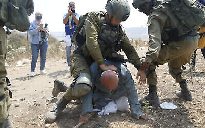 Des soldats israéliens arrêtant le Palestinien Khairi Hanoun lors d'une manifestation contre l'expansion de la présence juive, dans le village de Shufah en Cisjordanie, le 1ᵉʳ septembre 2020. (Crédit : Majdi Mohammed/AP)
