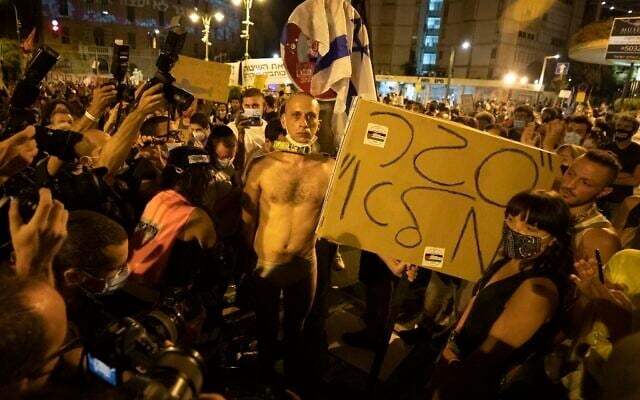 Un manifestant tient une pancarte sur laquelle on peut lire "Fermeture totale" en hébreu, après s'être enchaîné lors d'une manifestation contre le Premier ministre Benjamin Netanyahu devant sa résidence officielle à Jérusalem, le samedi 12 septembre 2020. (AP/Sebastian Scheiner) Un manifestant tient une pancarte sur laquelle on peut lire "Fermeture totale" en hébreu, après s'être enchaîné lors d'une manifestation contre le Premier ministre Benjamin Netanyahu devant sa résidence officielle à Jérusalem, le samedi 12 septembre 2020. (AP/Sebastian Scheiner)